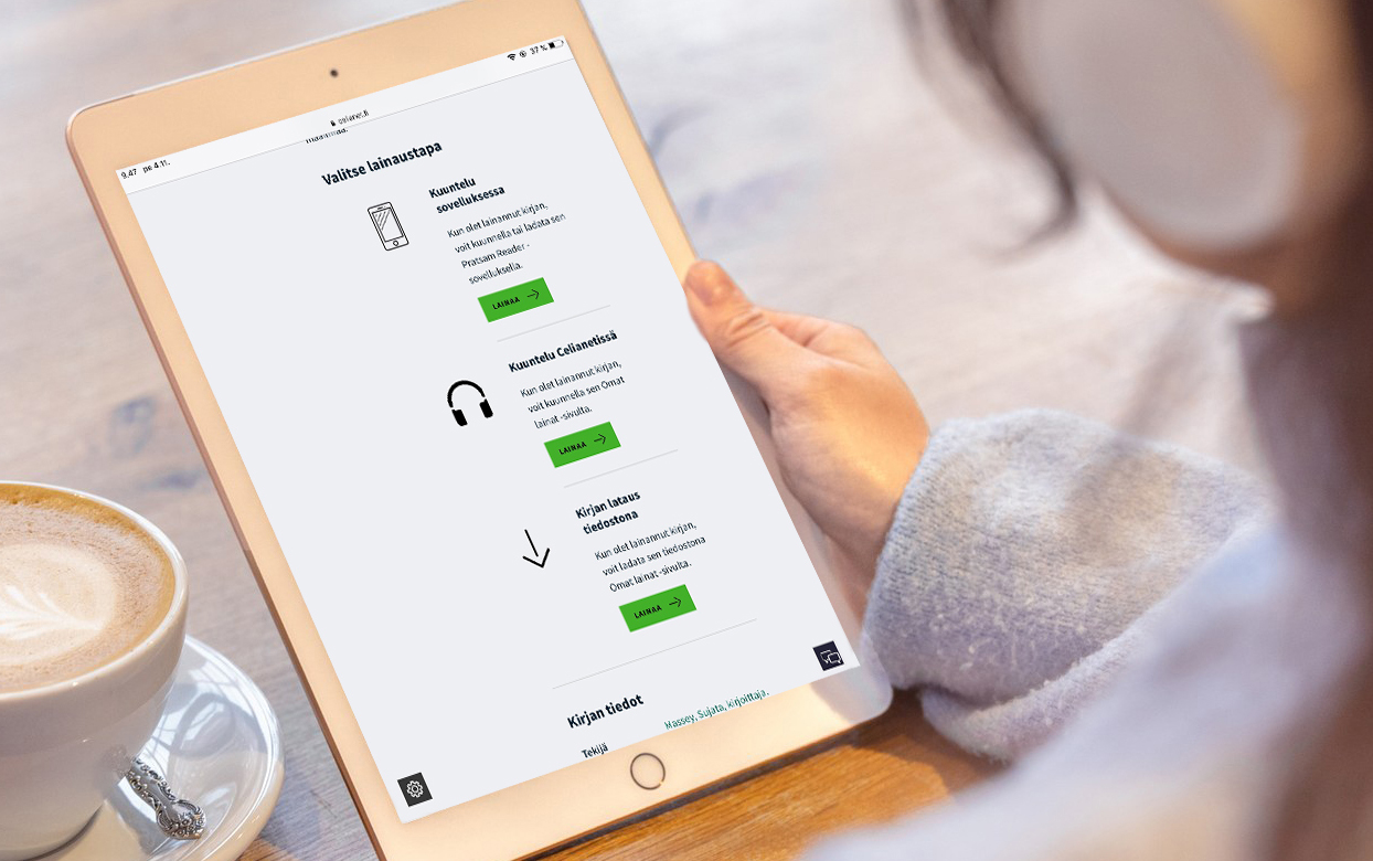 Henkilö pitää kadessaan tabletia, jossa on avoinna Saavutettavuuskirjasto Celian Celianet-äänikirjapalvelu. Pöydällä vieressä kahvikuppi.